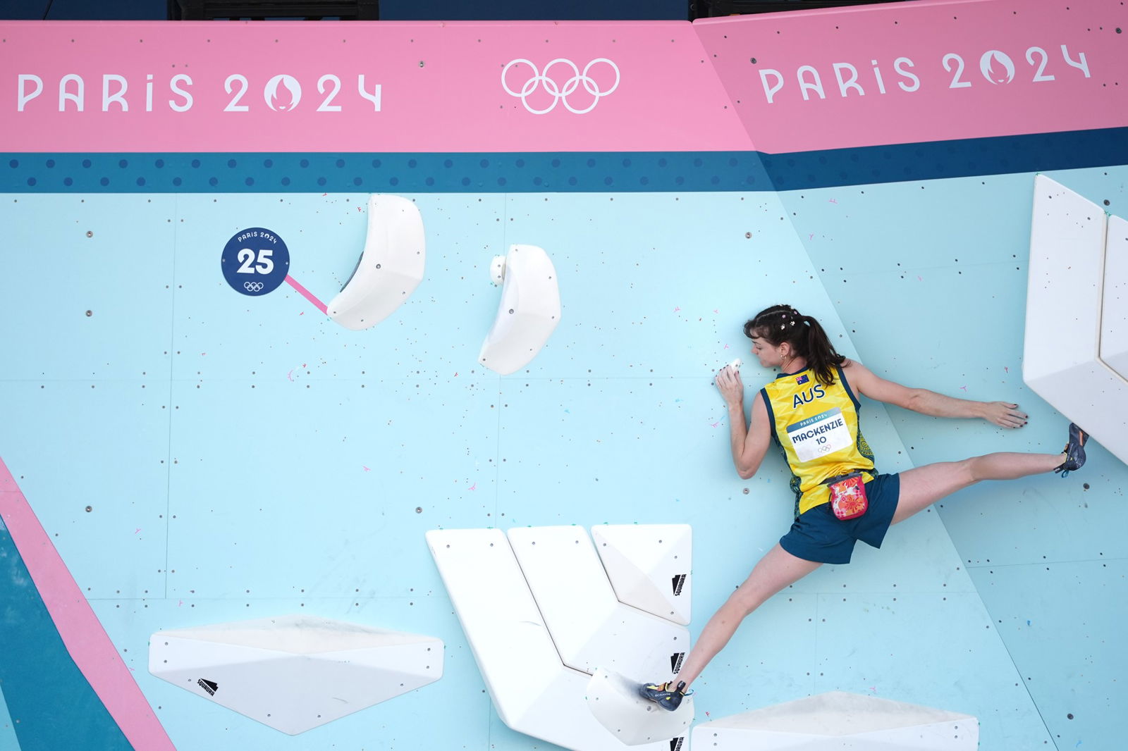 Australian climber Oceania Mackenzie stands with her legs a long way apart during a boulder problem at the Paris Olympics.