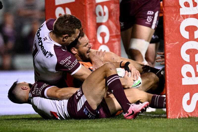 Aidan Sezer of the Wests Tigers is held up on the goal line by Luke&nbsp;Brooks (left) and Tom Trbojevic of the Sea Eagles