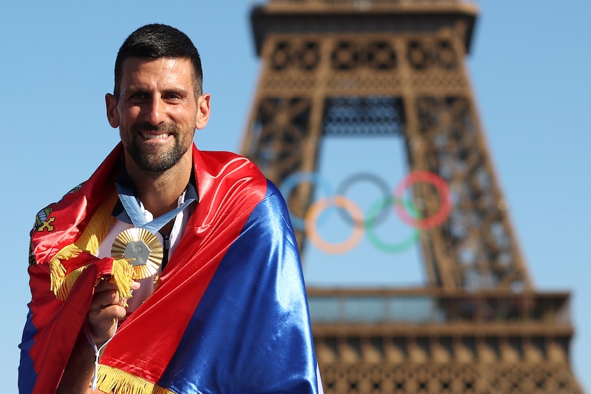 Novak Djokovic holds a gold medal in front of the Eiffel Tower