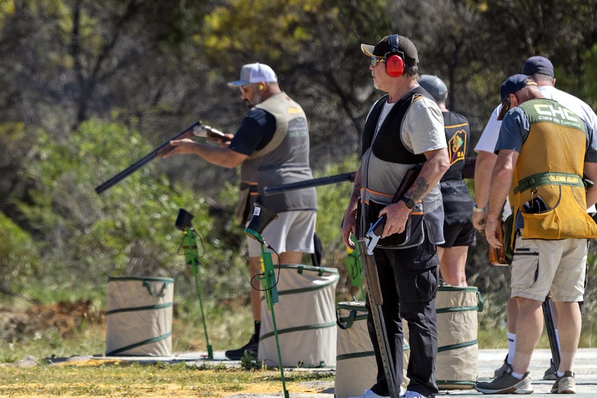 Participants at the shooting line, hold guns, ready to shoot