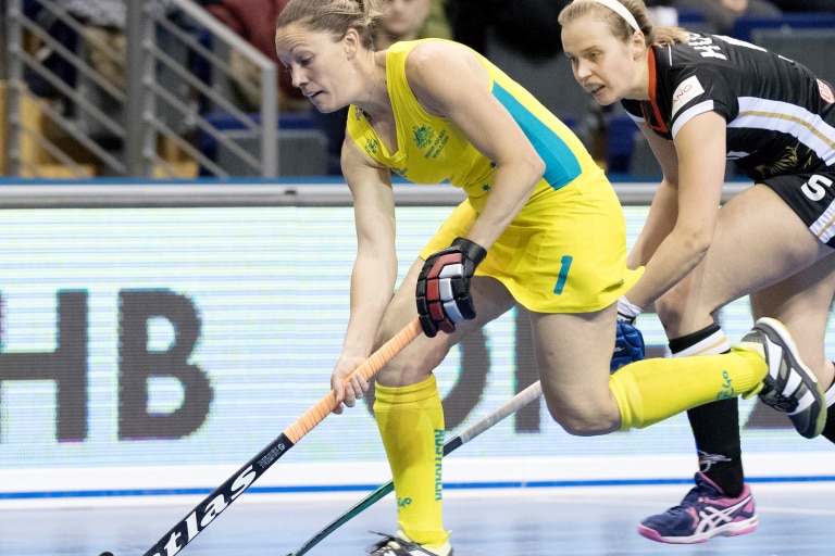 Lauren playing hockey dressed in green and yellow 