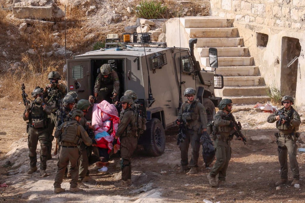 Israeli security forces transport the body of a Palestinian man from an old building to a military vehicle during a raid in Hebron city in the occupied West Bank, September 1, 2024. Photo: AFP