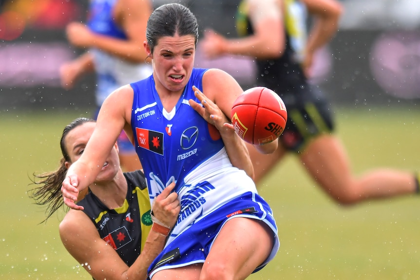 North Melbourne's Bella Eddey tackled by a Richmond AFLW opponent.