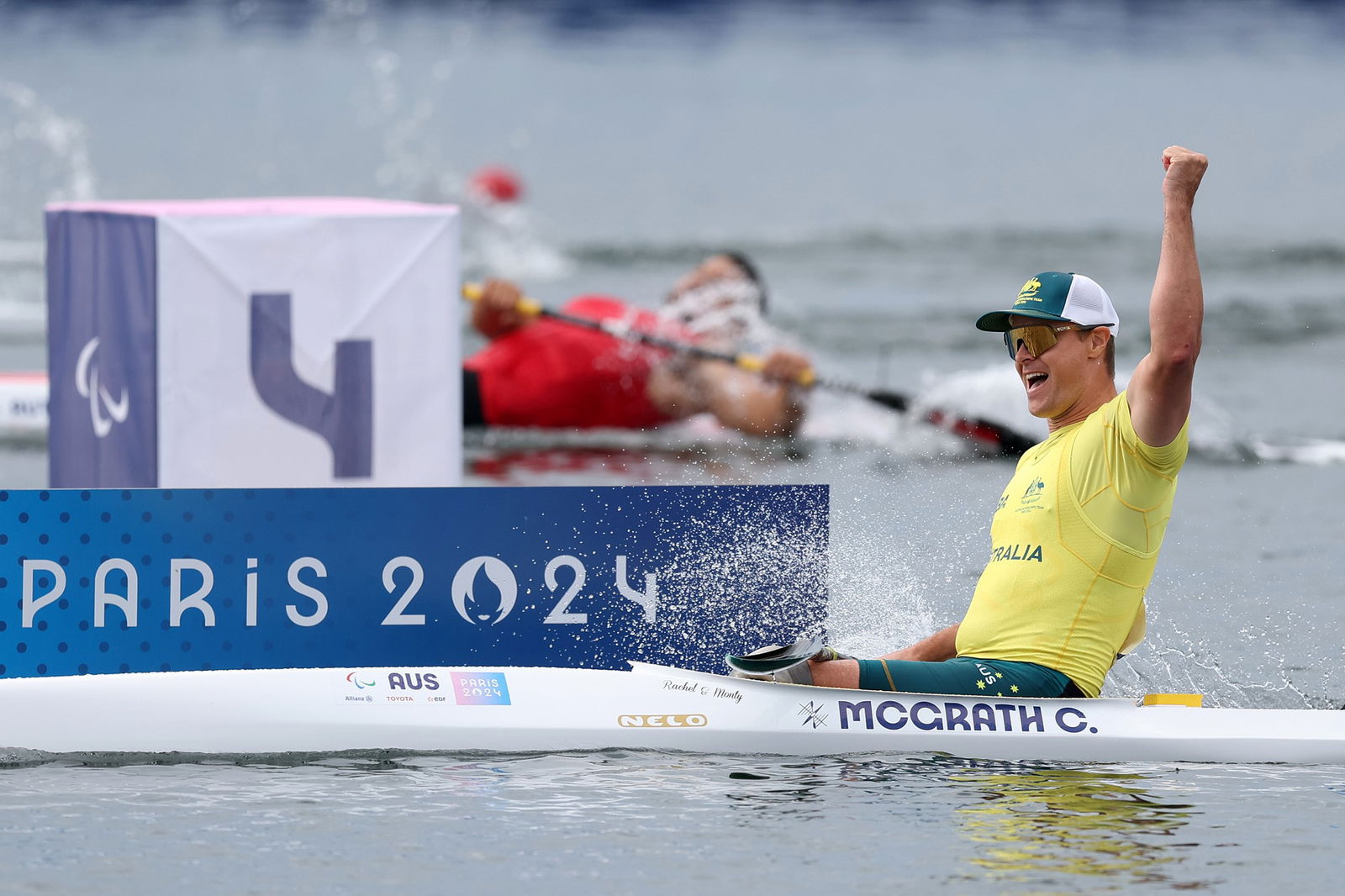 Australian Para canoeist has his arm raised triumphantly as he cheers and celebrates winning gold.
