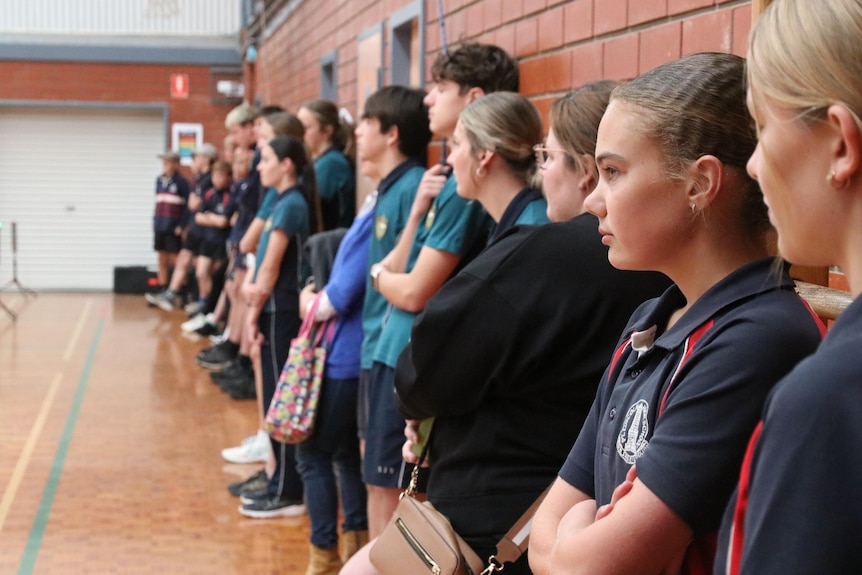 A row of children look on to someone speaking off camera