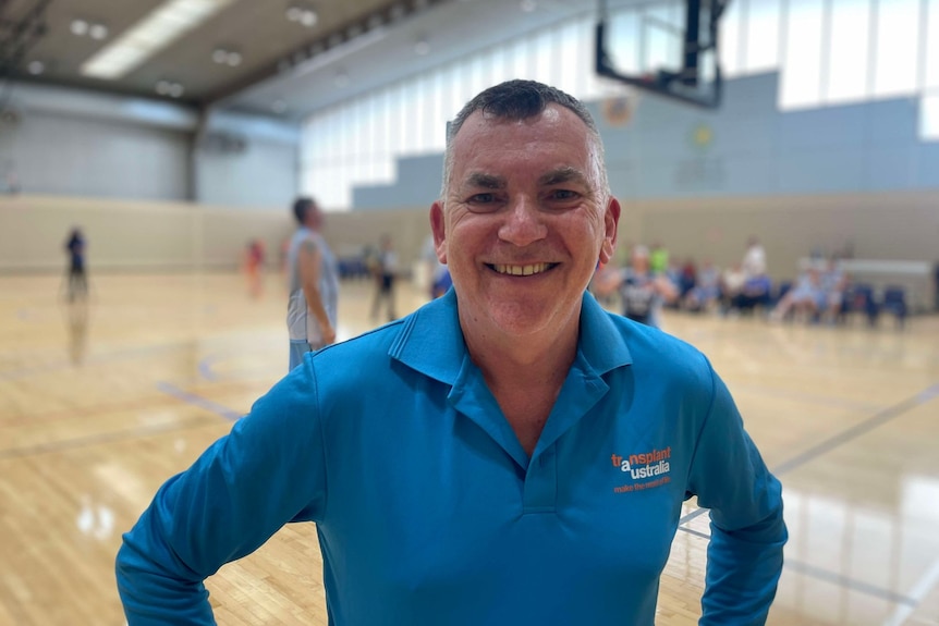 A man smiles on a basketball court.