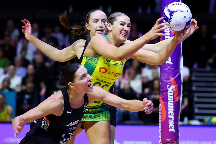 Australia's Sophie Garbin catches the ball in between two New Zealand players.