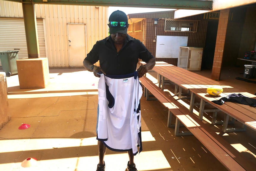 A man standing holding a ripped football jersey