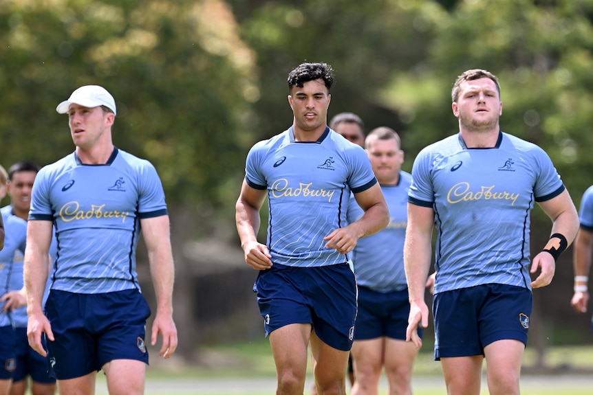 A group of Wallabies players wearing blue shirts complete a run during