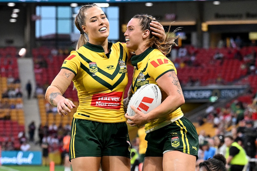 Isabelle Kelly hugs Julia Robinson after a try for Australia against PNG.