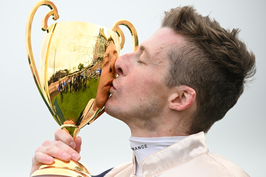 Harry Coffey kisses the Caulfield Cup after his victory.