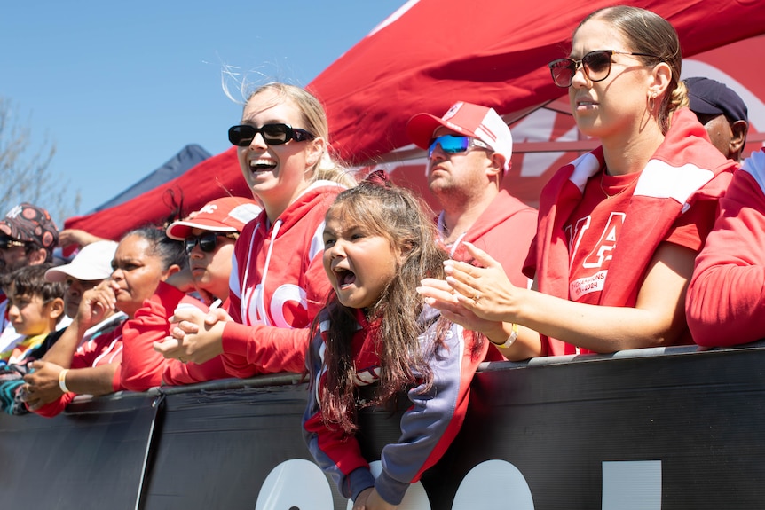 a young girl watching a football game, cheering on the sideline.