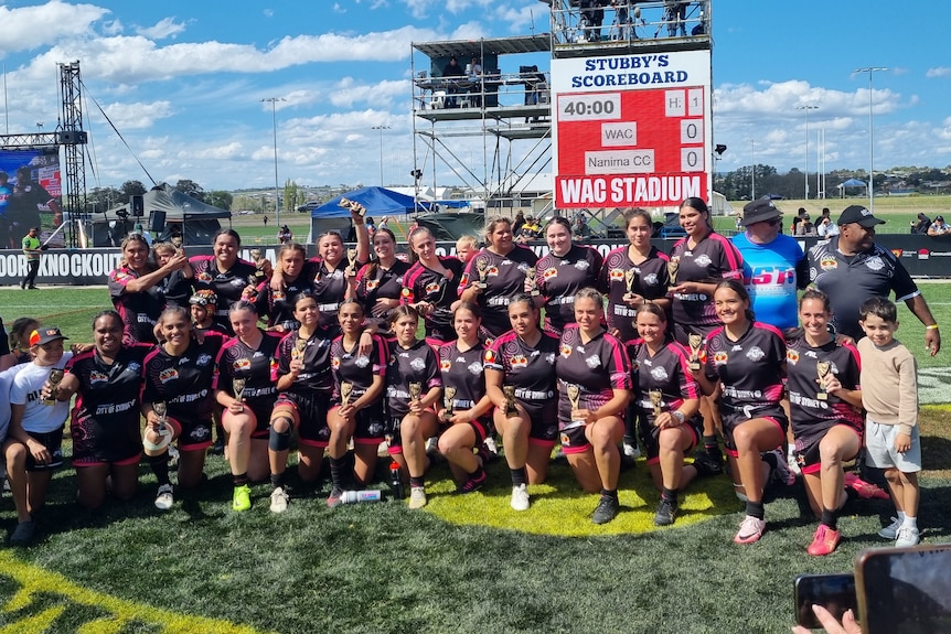 a football team pose for a photo together after winning a grand final