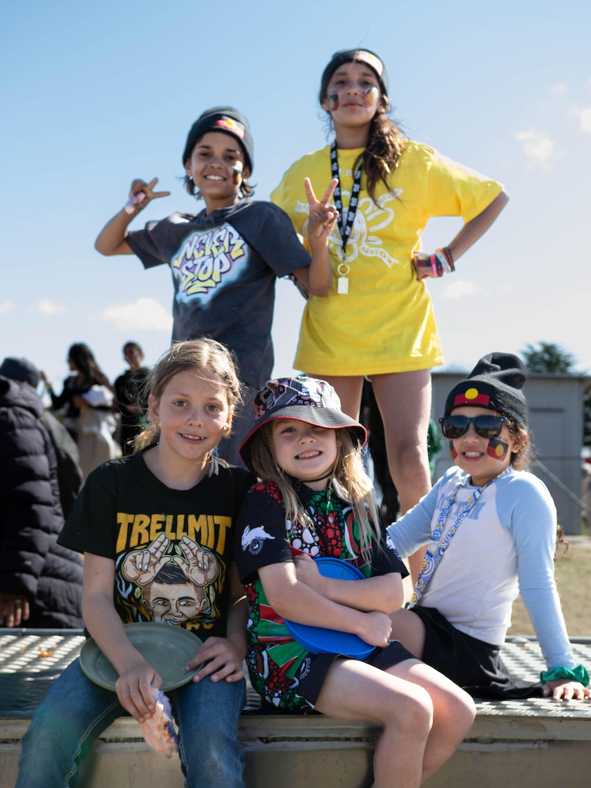 a group of kids at an indigenous football event smile at the camera