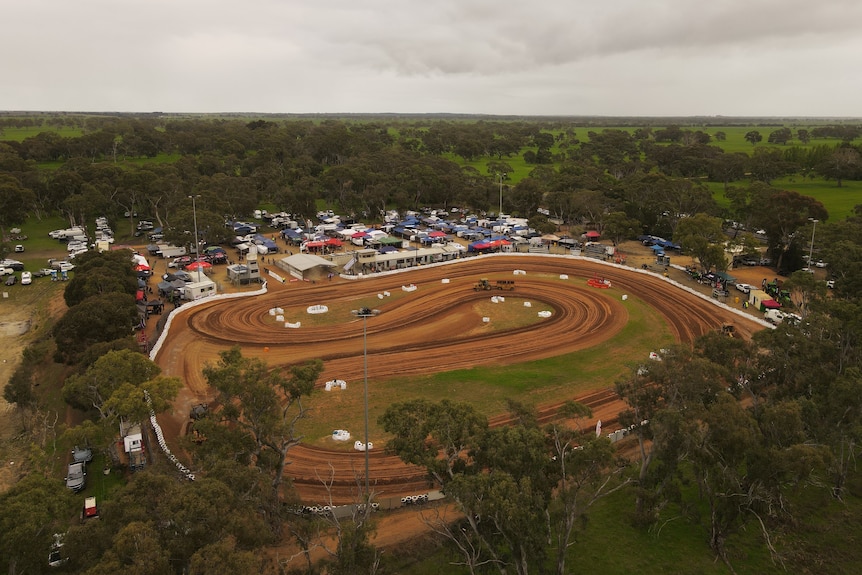 A drone photo of a dirt track with grandstands and lots of marquees and trailers