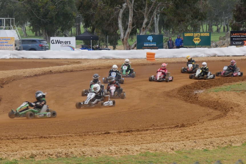 Go karts on a dirt track among tyres and gum trees
