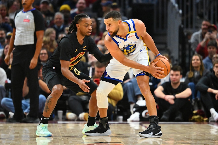 Darius Garland guards Stephen Curry who has the ball