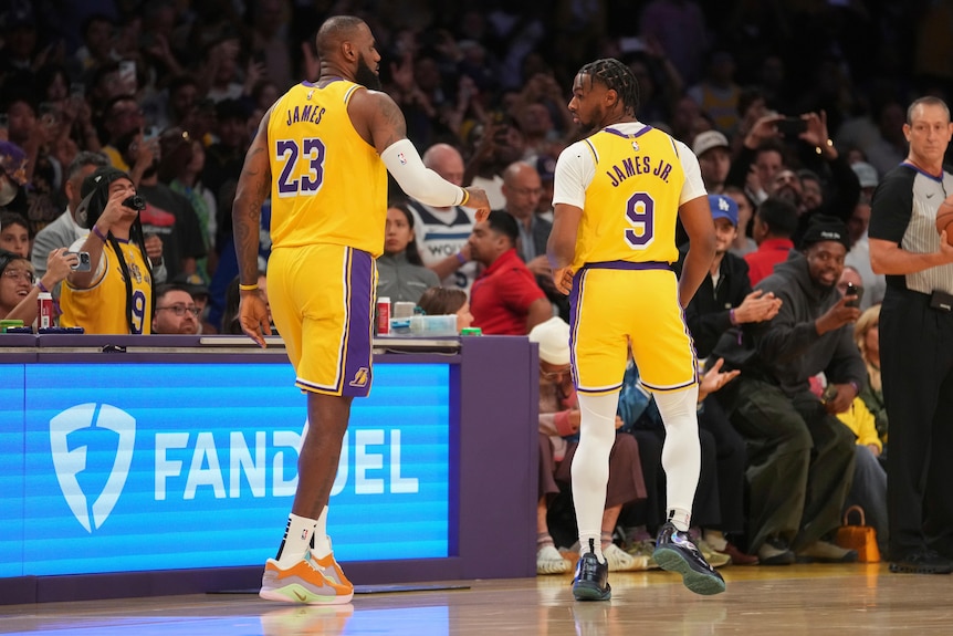 LeBron James and Bronny James walk onto the court together in an LA Lakers NBA game.