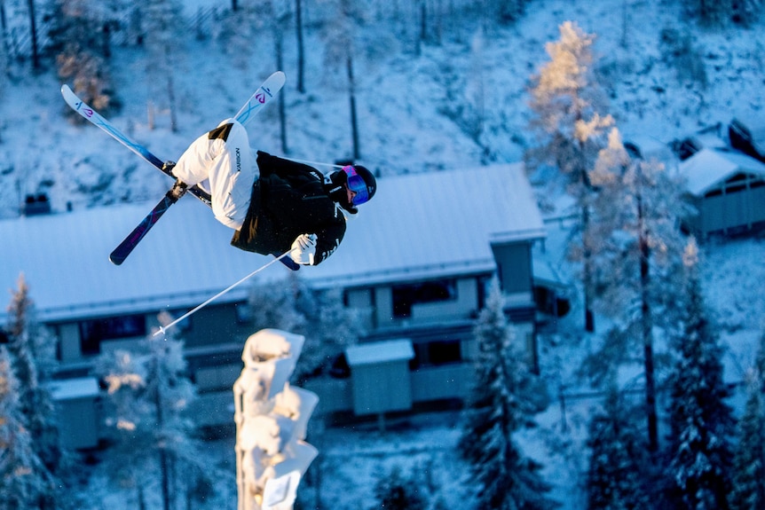 Jakara Anthony completes a jump with snow-topped buildings behind her