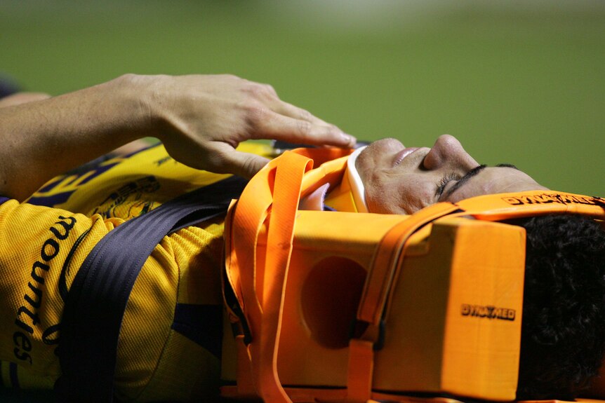 A man lies on a stretcher in a neck brace.