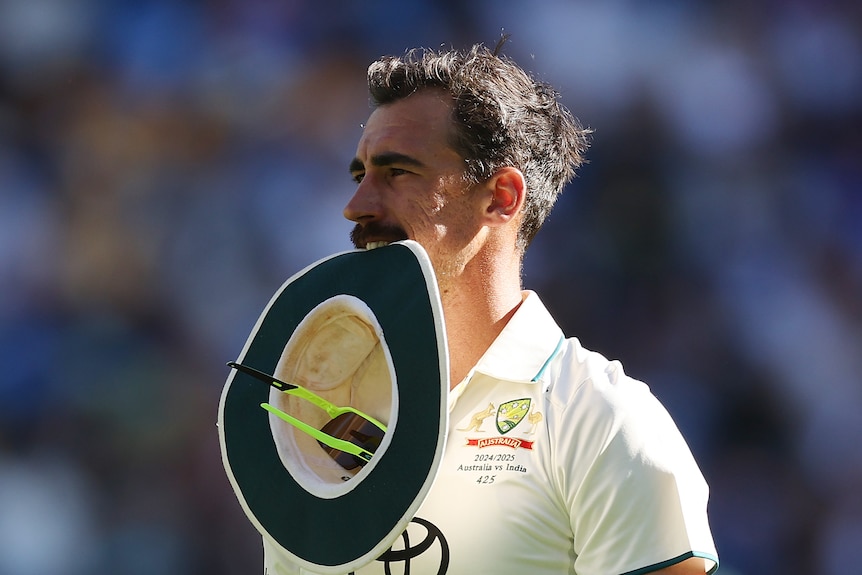 Mitchell Starc bites the top of his hat