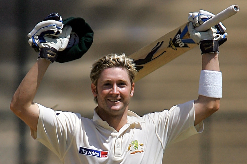 Michael Clarke smiles as he lifts his bat and cap during a Test match.