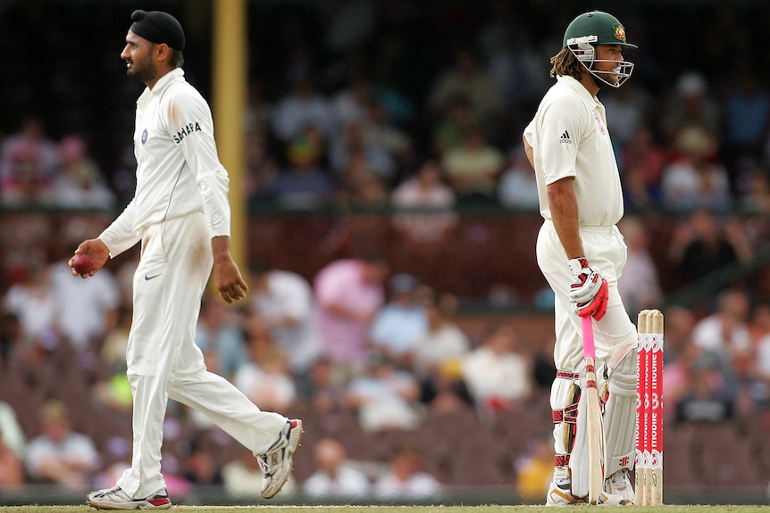 Harbhajan Singh walks past Andrew Symonds