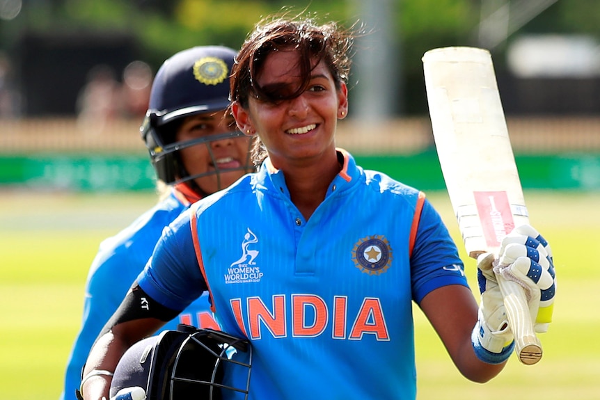 Harmanpreet Kaur holds up her bat and smiles