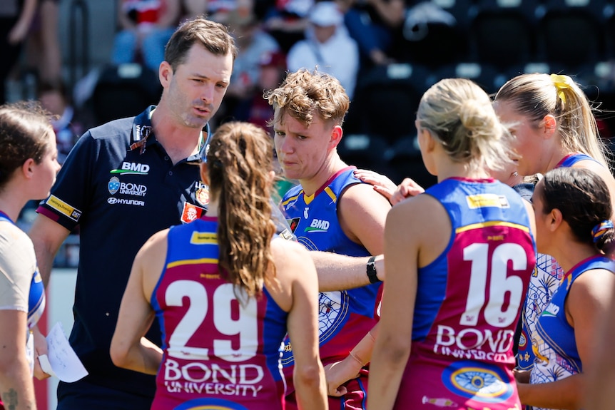 Brisbane Lions gather around AFLW teammate Dakota Davidson, who appears to be crying.