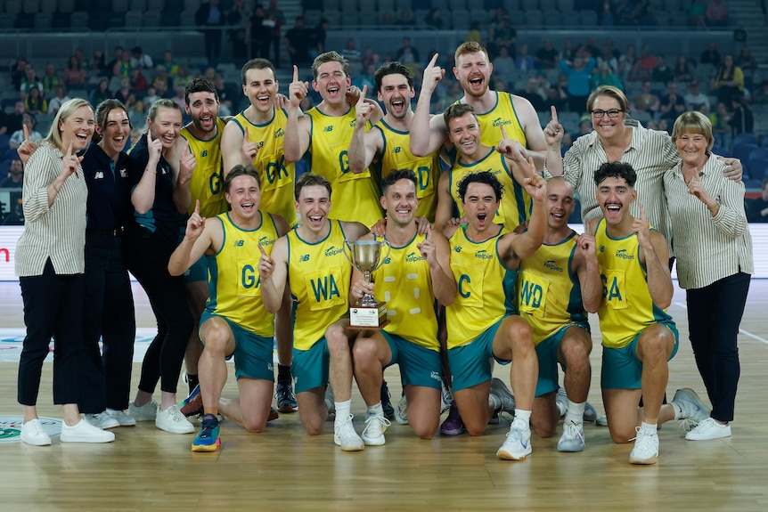 Male netball players gather together to post with a trophy and raise their fingers to indicate number one