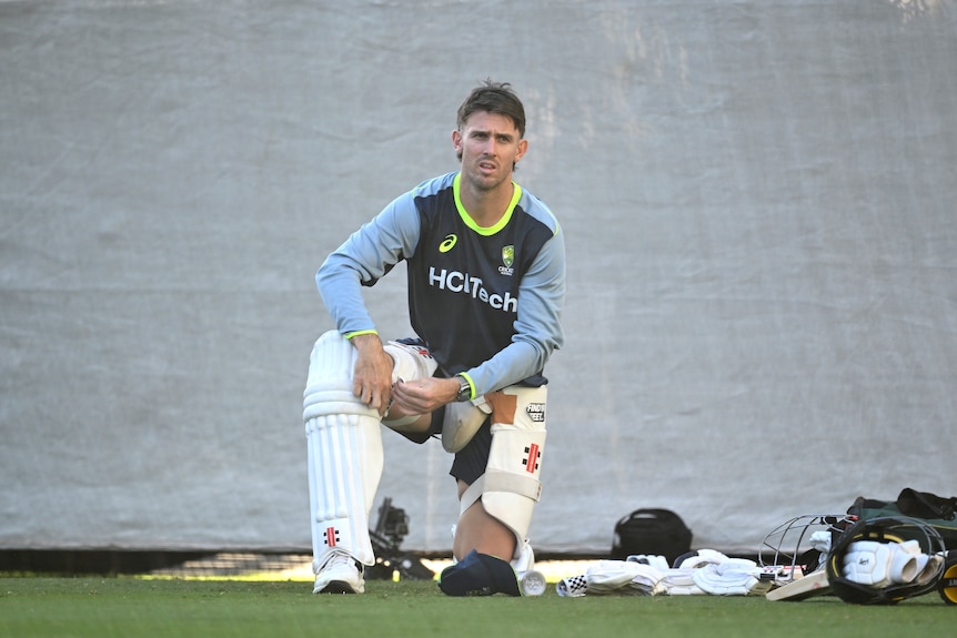 Mitch Marsh straps up his pads while kneeling