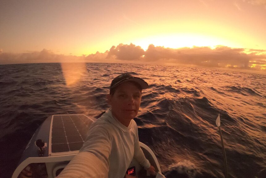 A woman on a small boat in the middle of the ocean at sunset