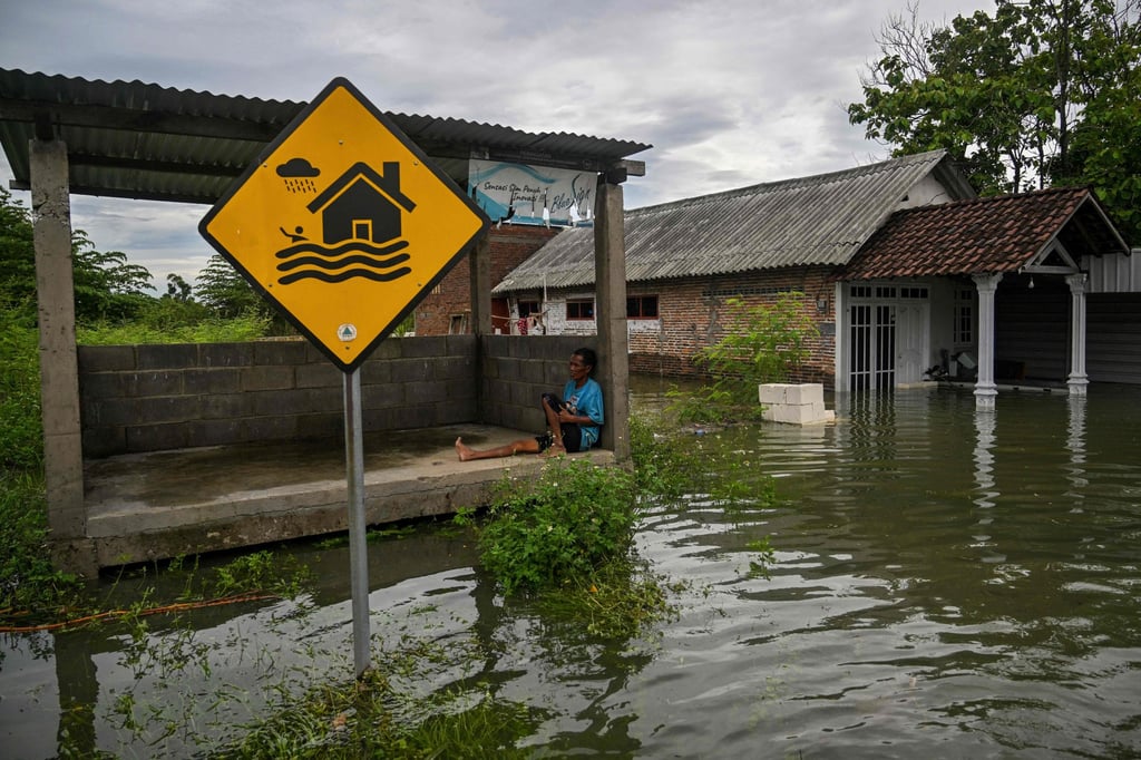 A man in Tempuran village, East Java province, rests in a hut surrounded by floodwaters on Monday. Photo: AFP