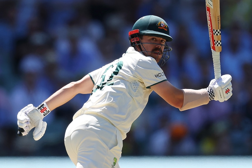 Australia batter Travis Head sets of for a run as he watches a cricket ball run away behind him.