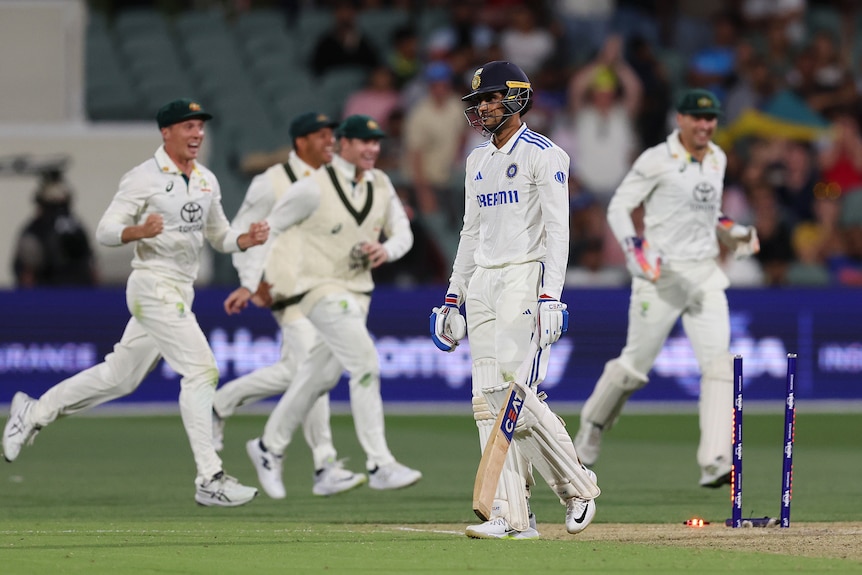 India batter Shubman Gill walks off as Australia fielders celebrates behind him. His stumps have been smashed.