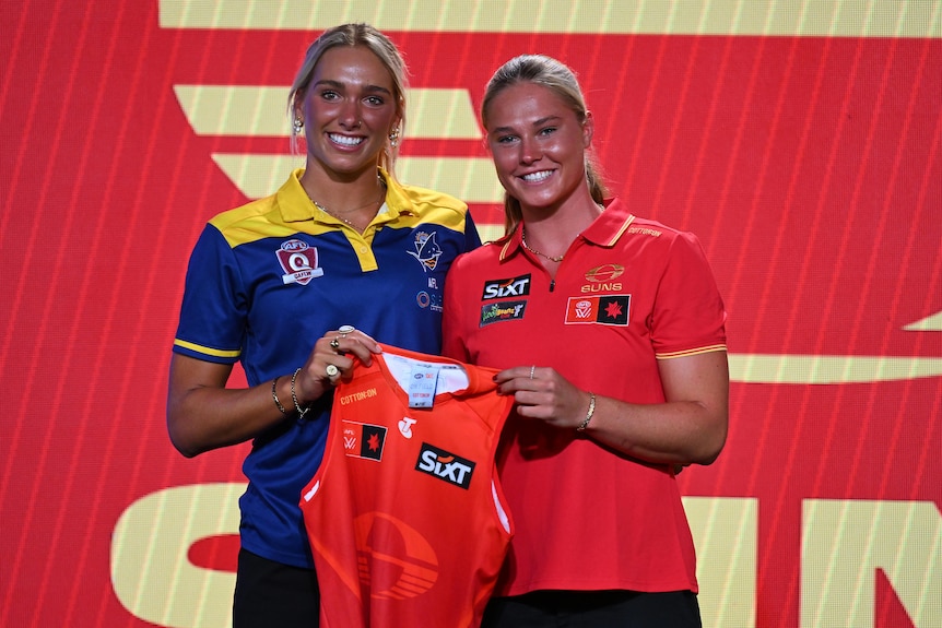 Havana Harris is presented with a Gold Coast Suns guernsey by a new teammate at the AFLW draft