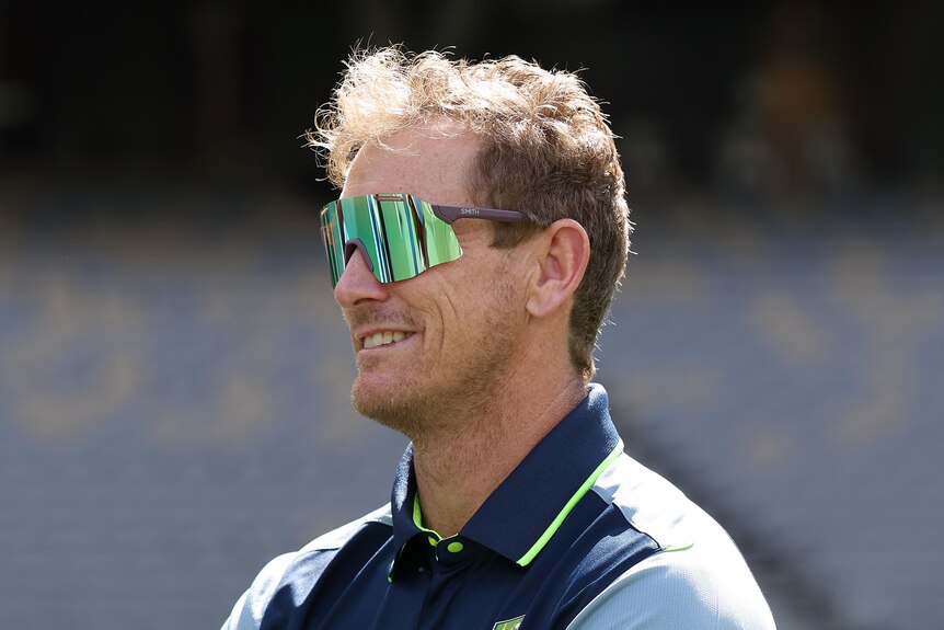 George Bailey stands with his arms folded