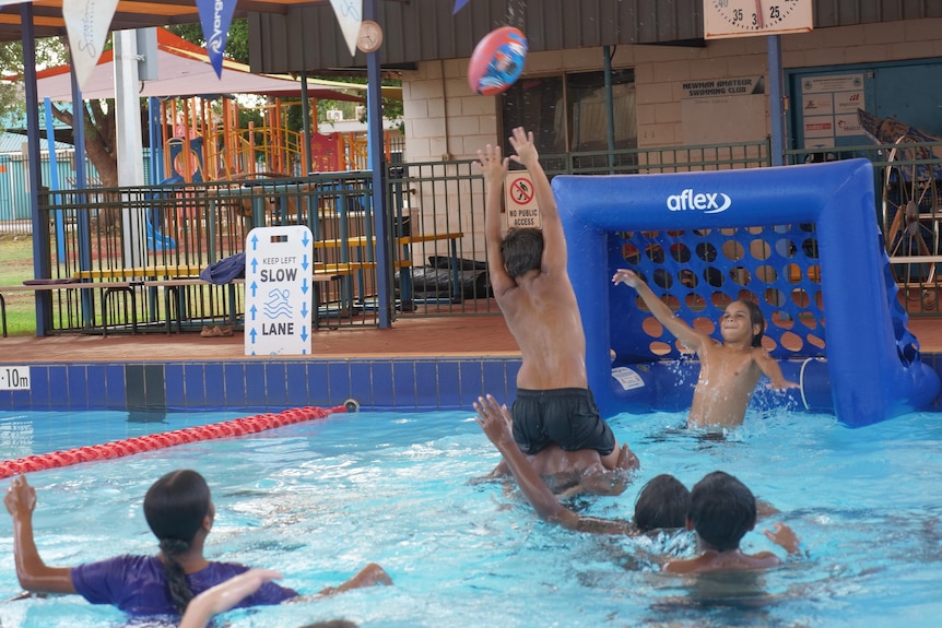 A group of young people with hands up as they go for a football