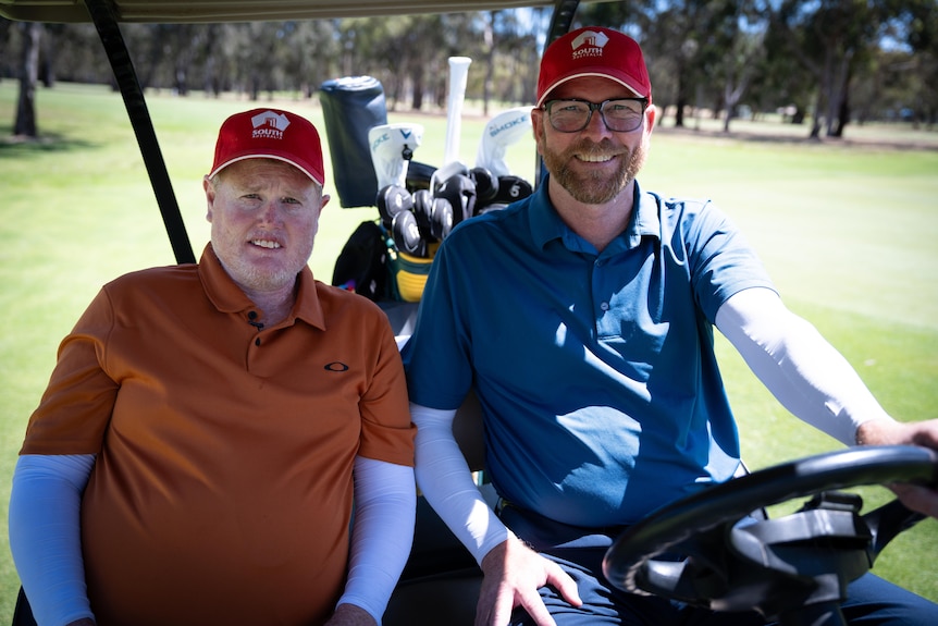 Steven Alderson and Trent Blucher sit side by side in a golf buggy