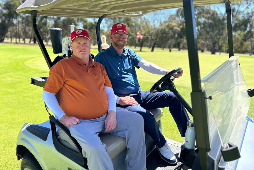 Steven Alderson and his caddie Trent Blucher sitting in a golf buggy