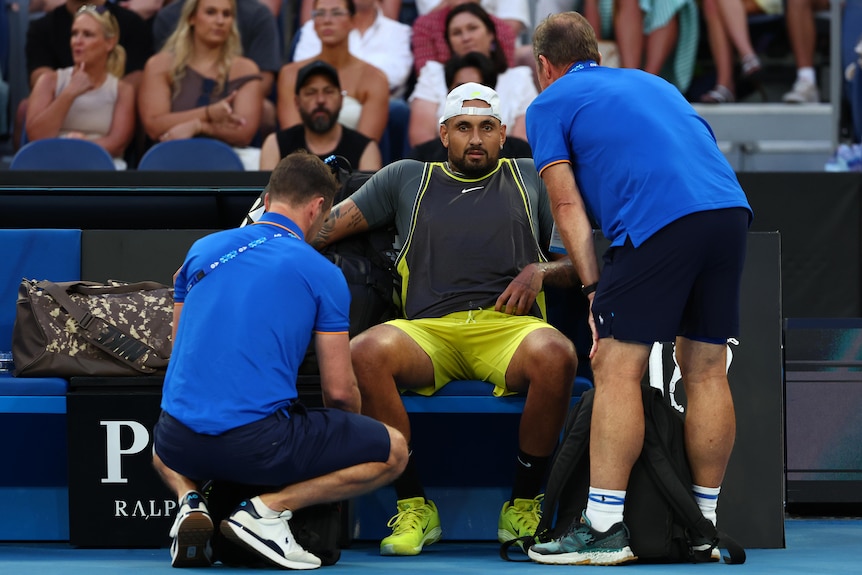 Nick Kyrgios is attended to by two physios