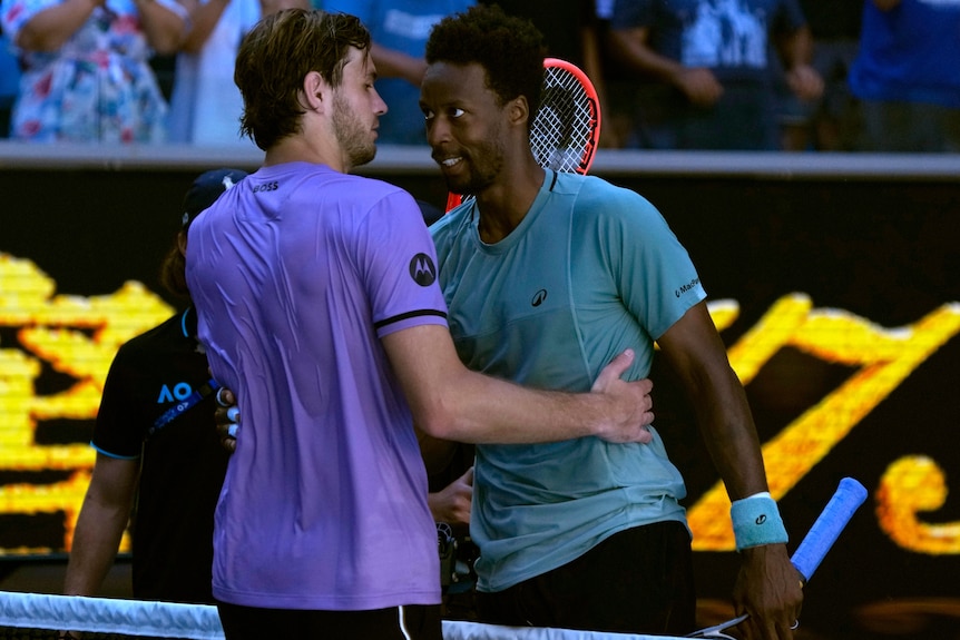 Gael Monfils and Taylor Fritz embrace each other at the net at the Australian Open.