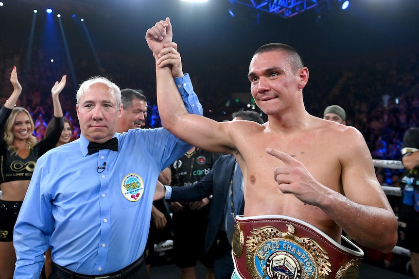 Tim Tszyu has his arm raised with a boxing belt around his waist