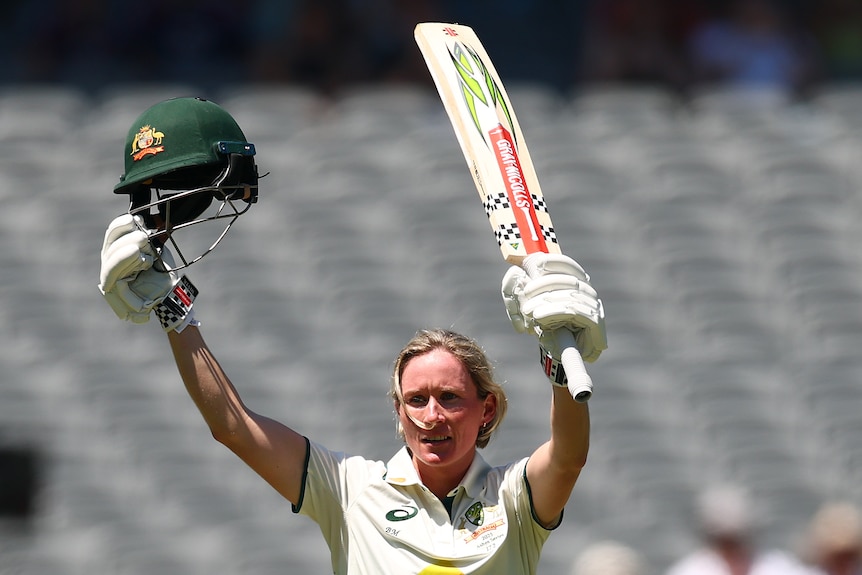 Beth Mooney holds up her bat and helmet
