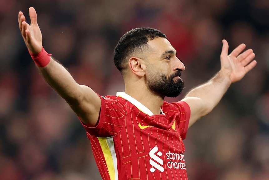 Mohamed Salah stands with his arms held wide as he celebrates a Liverpool goal.