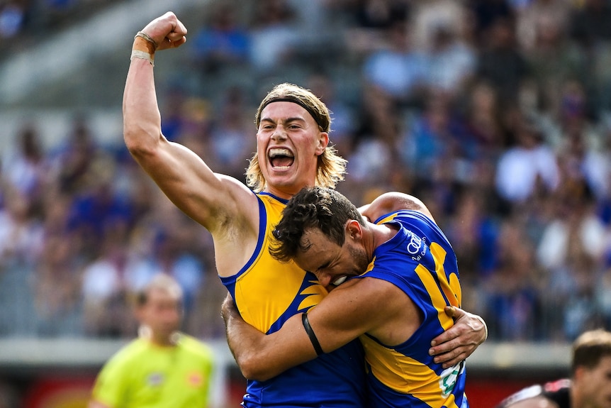 Harley Reid, pumping his fist, being hugged by a teammate, during an AFL match