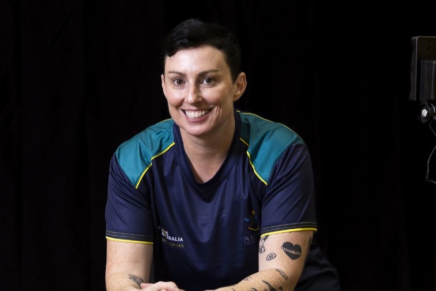 a woman in a blue and teal shirt smiles at the camera