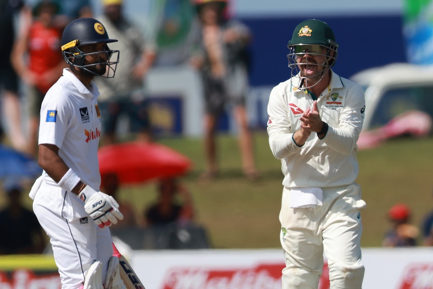 Australia fielder Travis Head claps and shouts in front of dismissed Sri Lanka batter Dinesh Chandimal.