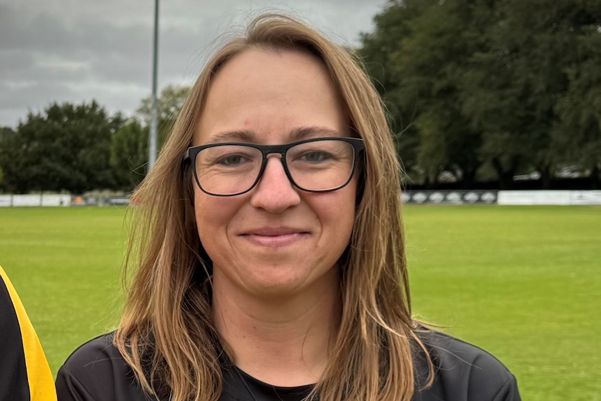 a photo of a woman smiling at the camera on a football field 