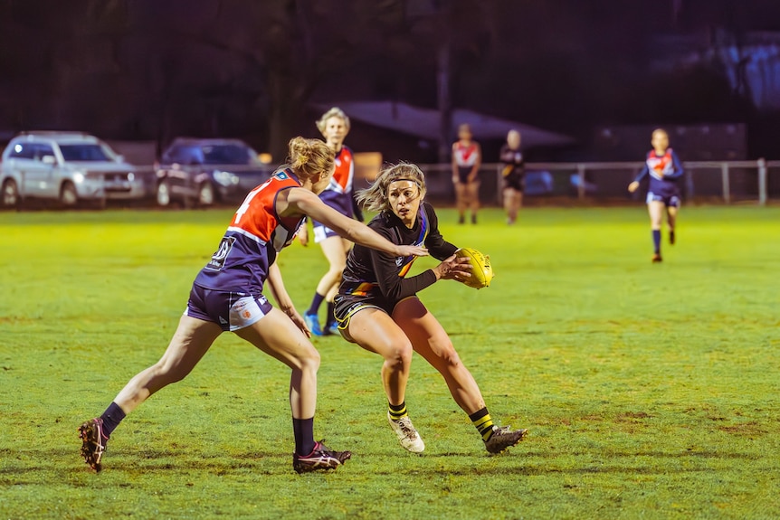a photo of a female tackling another with a football on a football field 